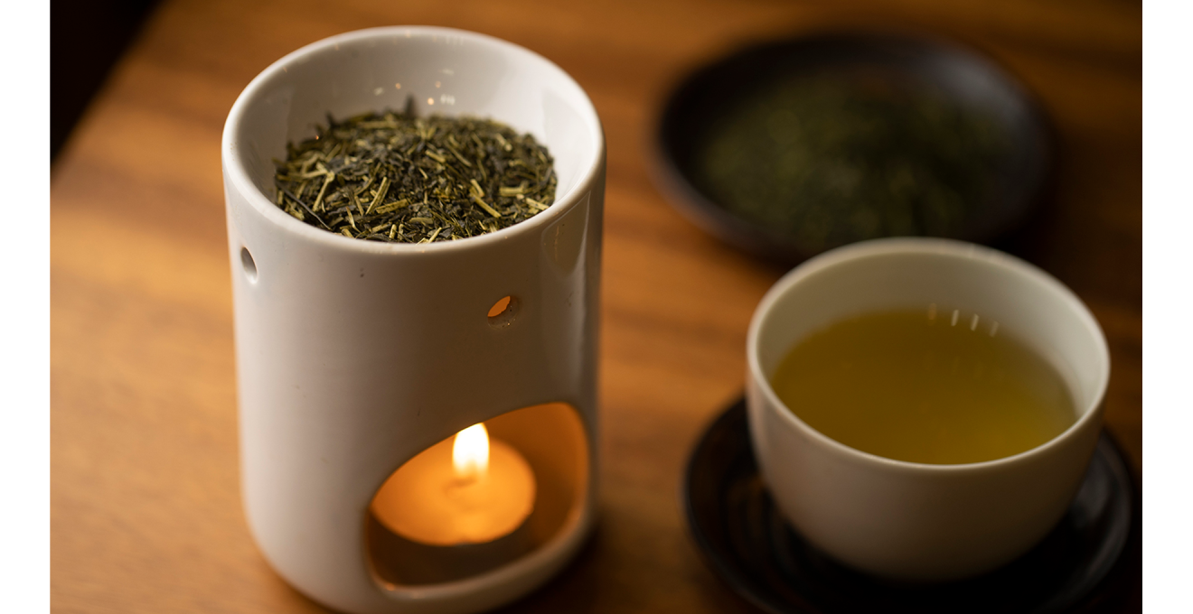茶香炉のロウソクに火がつけられ、茶葉を焙じている写真。そばにはお茶もある。