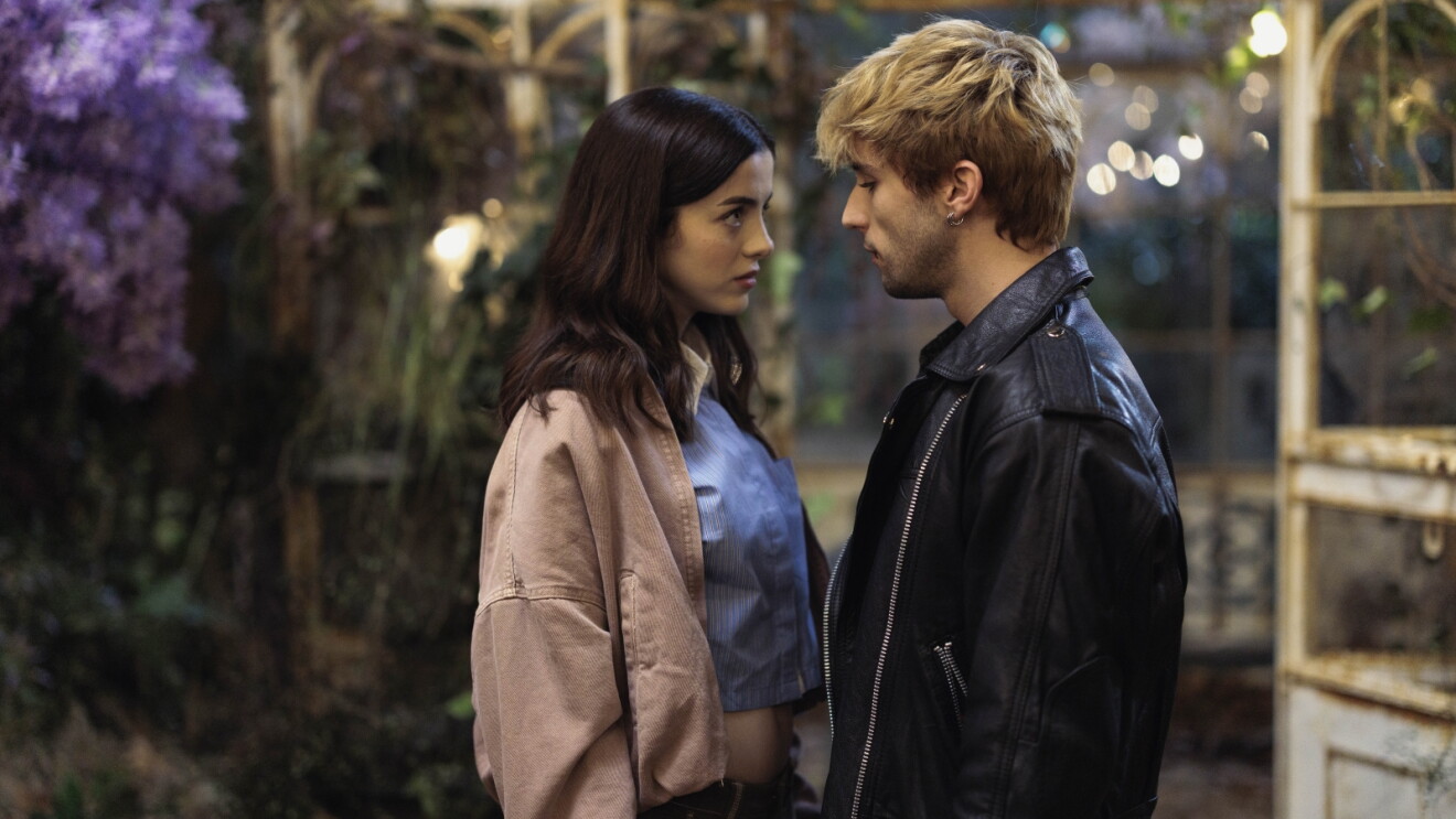 Still from 'Boulevard': Two people facing each other in an intense conversation with purple flowers in the background