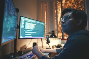 José Tapia, sitting at a desk, viewing information on two computer monitors.