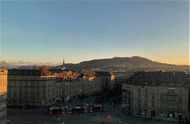 Ausblick auf die Innenstadt von Bern bei Sonnenaufgang. Im Hintergrund sind die Berge zu sehen.