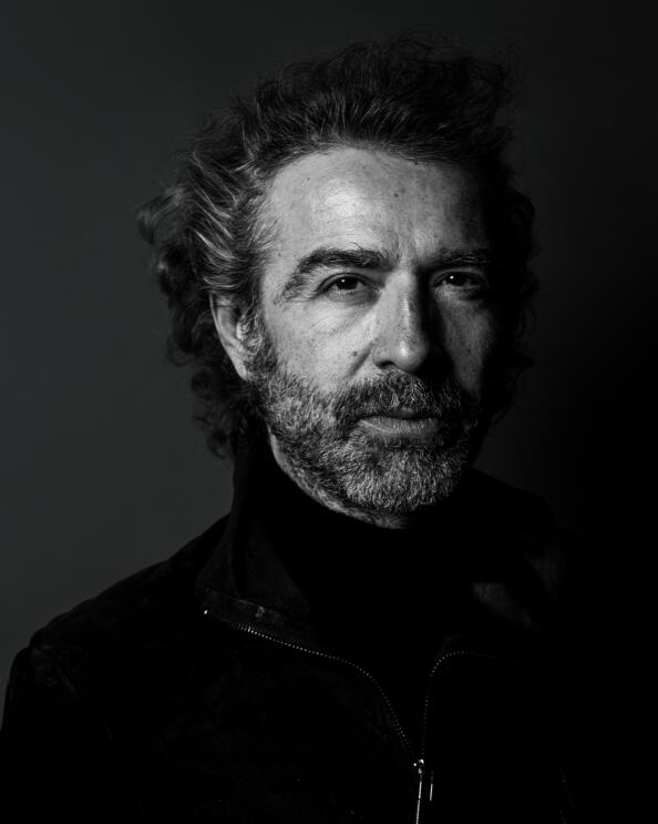 Schwarz-weiß Porträt-Foto von Christof Straub, CEO von Global Rockstar, er trägt Vollbart, das Haar ist leicht gelockt und grau meliert. Er trägt einen schwarzen Rollkragenpullover und darüber eine schwarze Jacke.