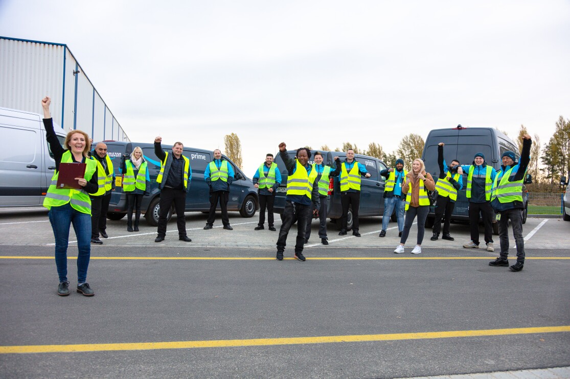 Teambild: Amazon Lieferpartnerin Irena mit ihren Fahrern auf dem Fuhrparkgelände