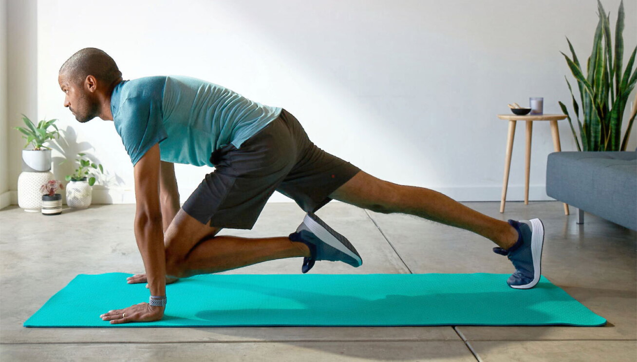 A man working out at home using a green yoga mat.