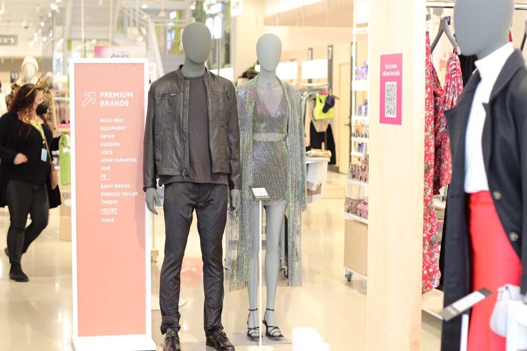 A display of clothing on two mannequins. One is a man wearing an all black outfit with a leather jacket and the other is a woman wearing a sparkly halter top and skirt set with a sparkly duster jacket.