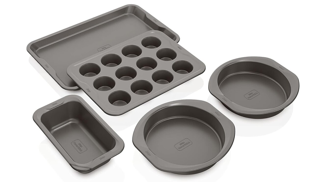 An image of five different baking pans, including a large baking sheet, a cupcake sheet, two round pans, and a small rectangular pan. They are all dark gray.