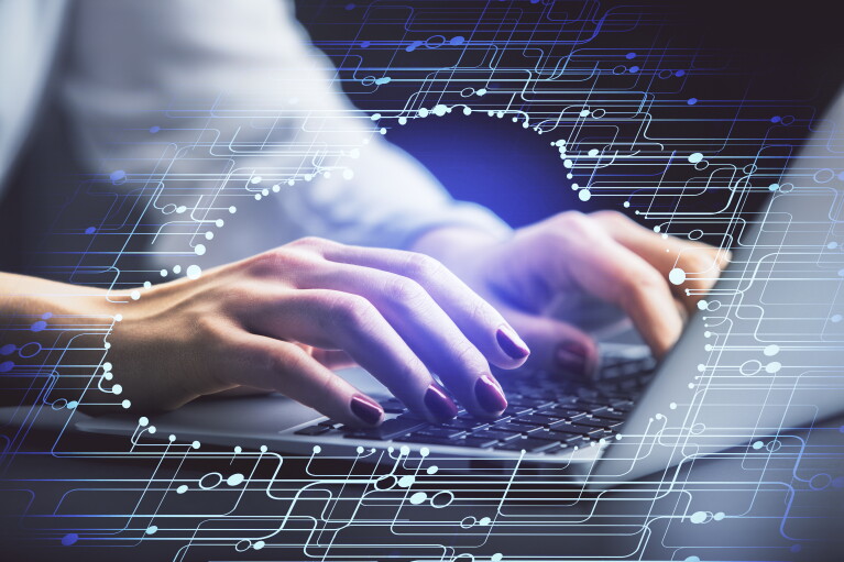 A woman's hands hover over a laptop as she works