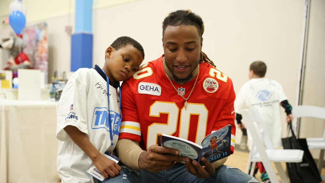 Kansas City Chiefs player Justin Reid reads a book with a child at a "TNF for Good" event.