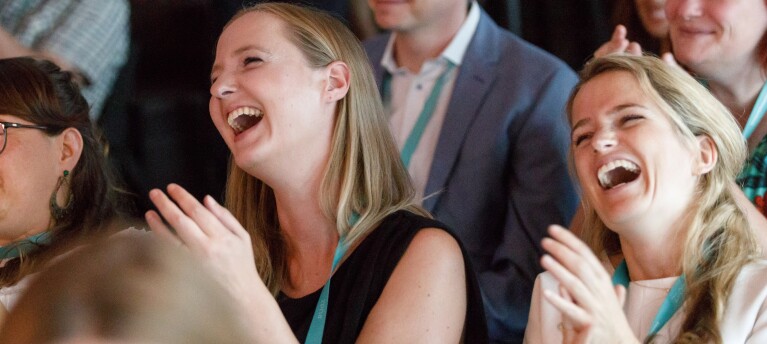 Zwei junge Damen sitzen im Publikum, klatschen und lachen laut