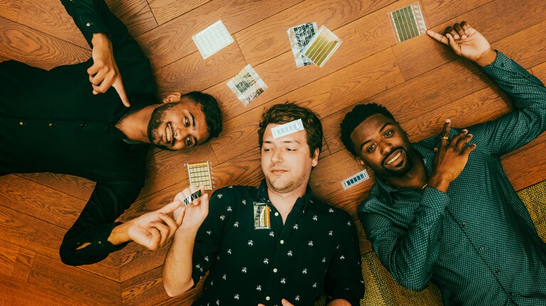 A photo of three adults laying on a wood floor.