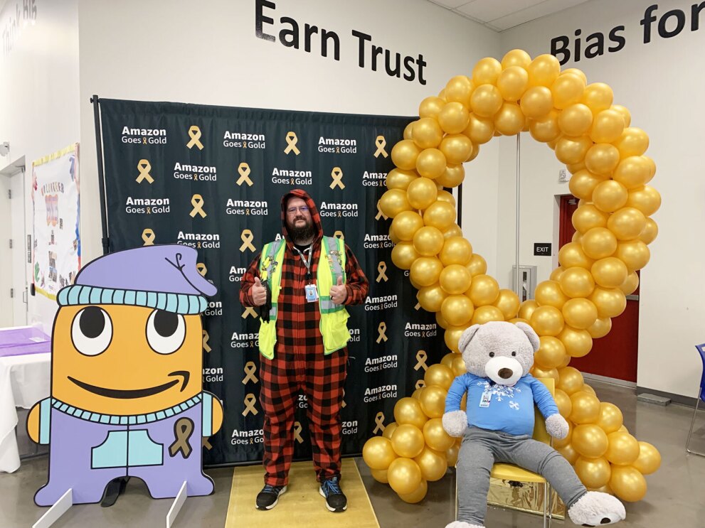 An Amazon employee wears a yellow safety vest and pajamas celebrating Amazon Goes Gold.