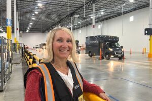 An image of a woman, an Amazon Delivery Service Partner, in a work vest standing in front of a delivery van.