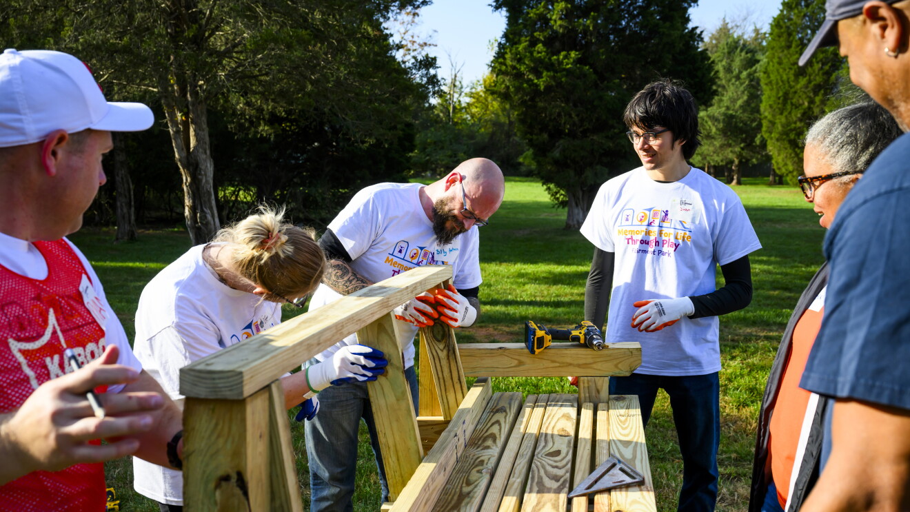KABOOM! and AWS: Volunteers in matching t-shirts constructing wooden structure outdoors