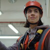 Foto aus der aktuellen Amazon Kampagne: Zu sehen ist das Porträt eine jungen Amazon Technikerin mit halblangen braunen Haaren. Sie trägt einen Sicherheitshelm und eine Sicherheitsweste.