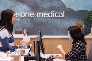 senior writer connie chen talking to the receptionist in front of a sign that says one medical, inside the nomad one medical office in new york city