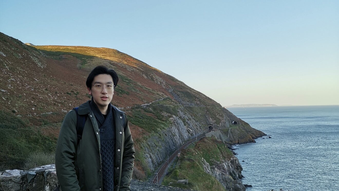 Fangbo Li standing in front of a coastal view