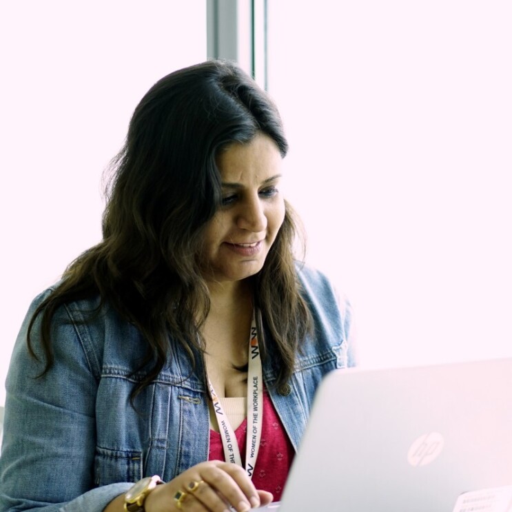 A woman works on her computer in a sun-drenched room.