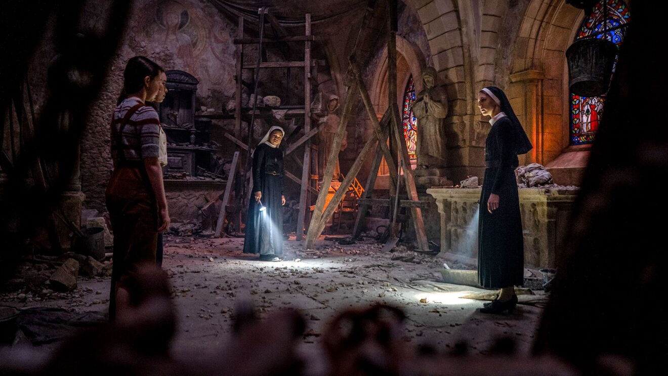 The Conjuring movie: Nuns and civilian explore damaged church interior with flashlights