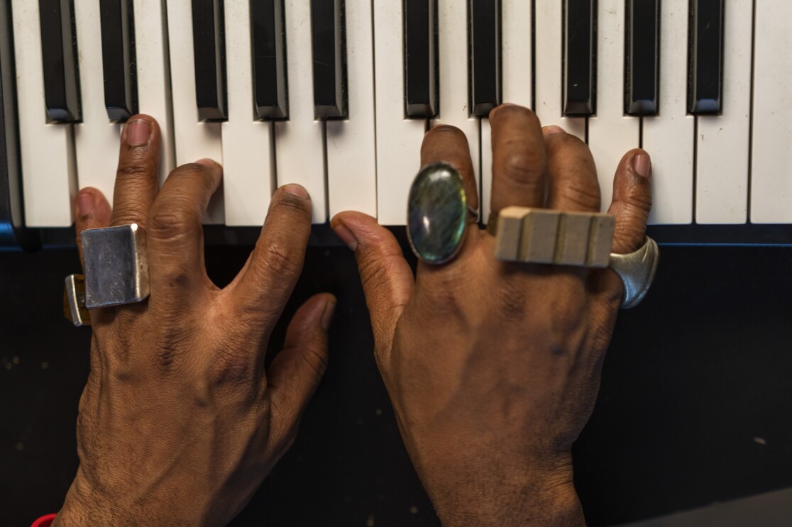 A person wearing rings plays music on a small keyboard.