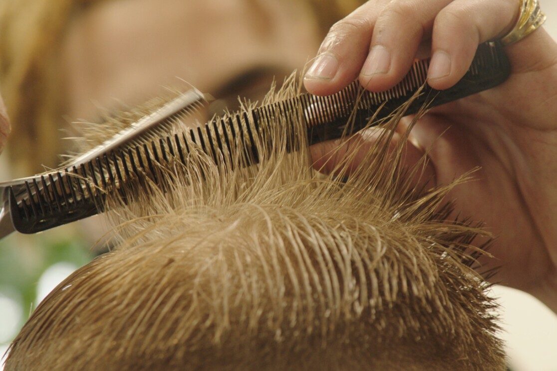 A close up image of the top of a head of someone getting their hair cut.