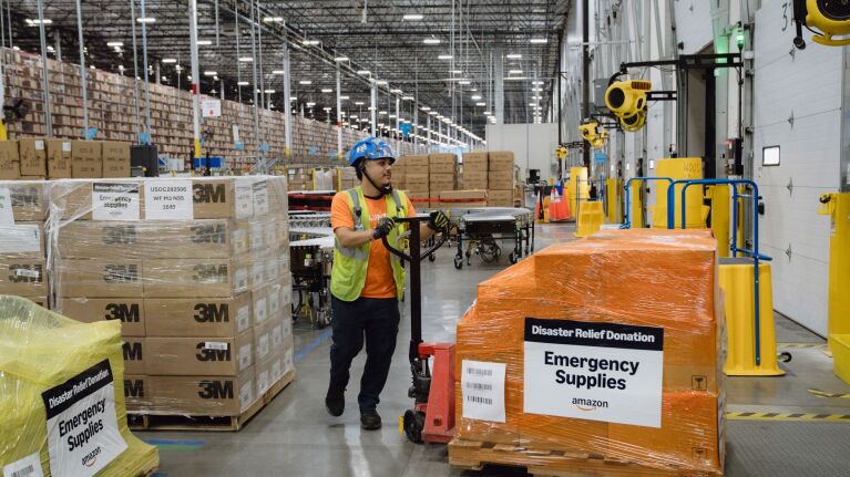 Amazon employee preparing emergency supplies and disaster relief donations in large fulfillment center