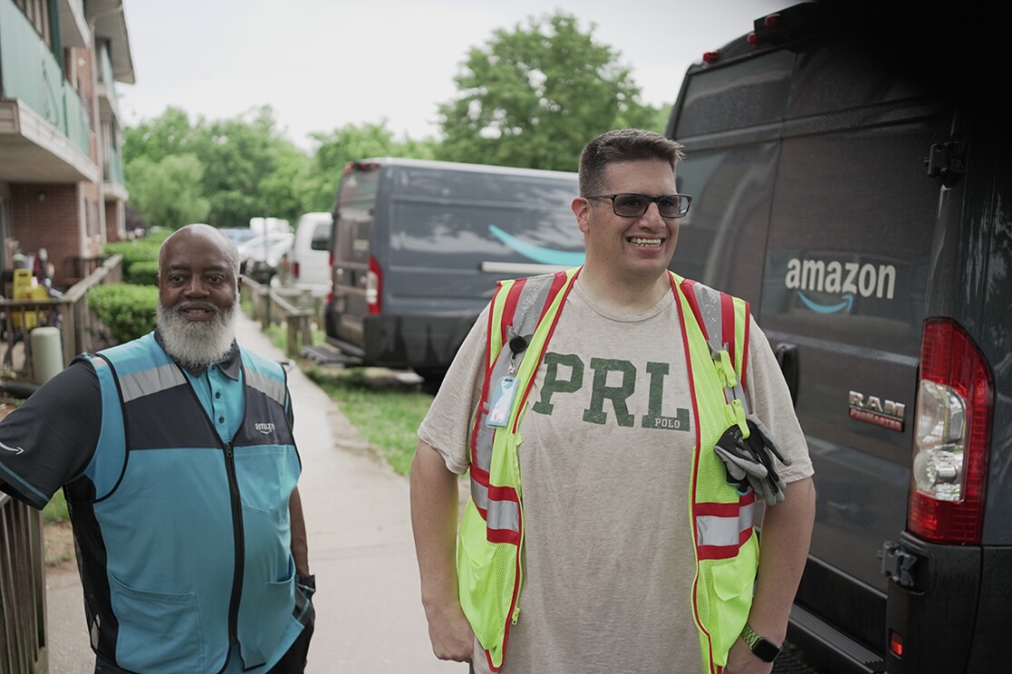 Volunteers and Amazon employees load up Amazon delivery vans with essential furniture and household products.