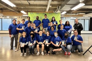 A group of Amazon employees wear blue Amazon T-shirts and hold hygiene packs to be sent to Ukraine.