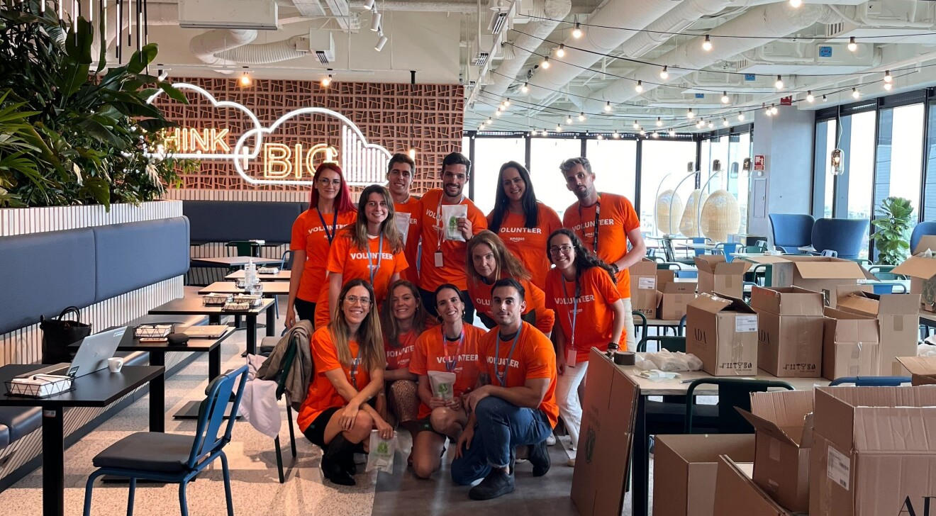Amazon Mitarbeiter:innen in orangenen T-Shirts in Spanien stellen Produkte für Spenden zusammen