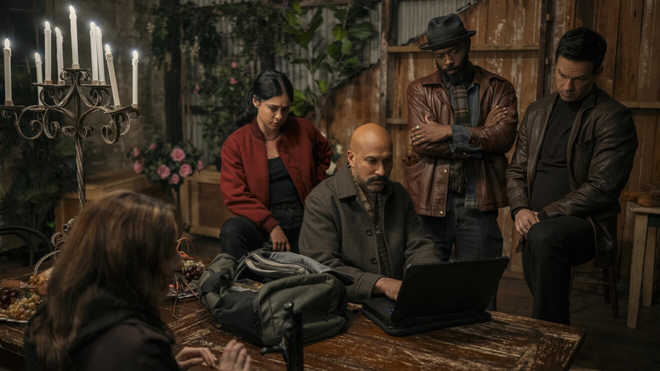 Group gathered around laptop in rustic setting with candelabra