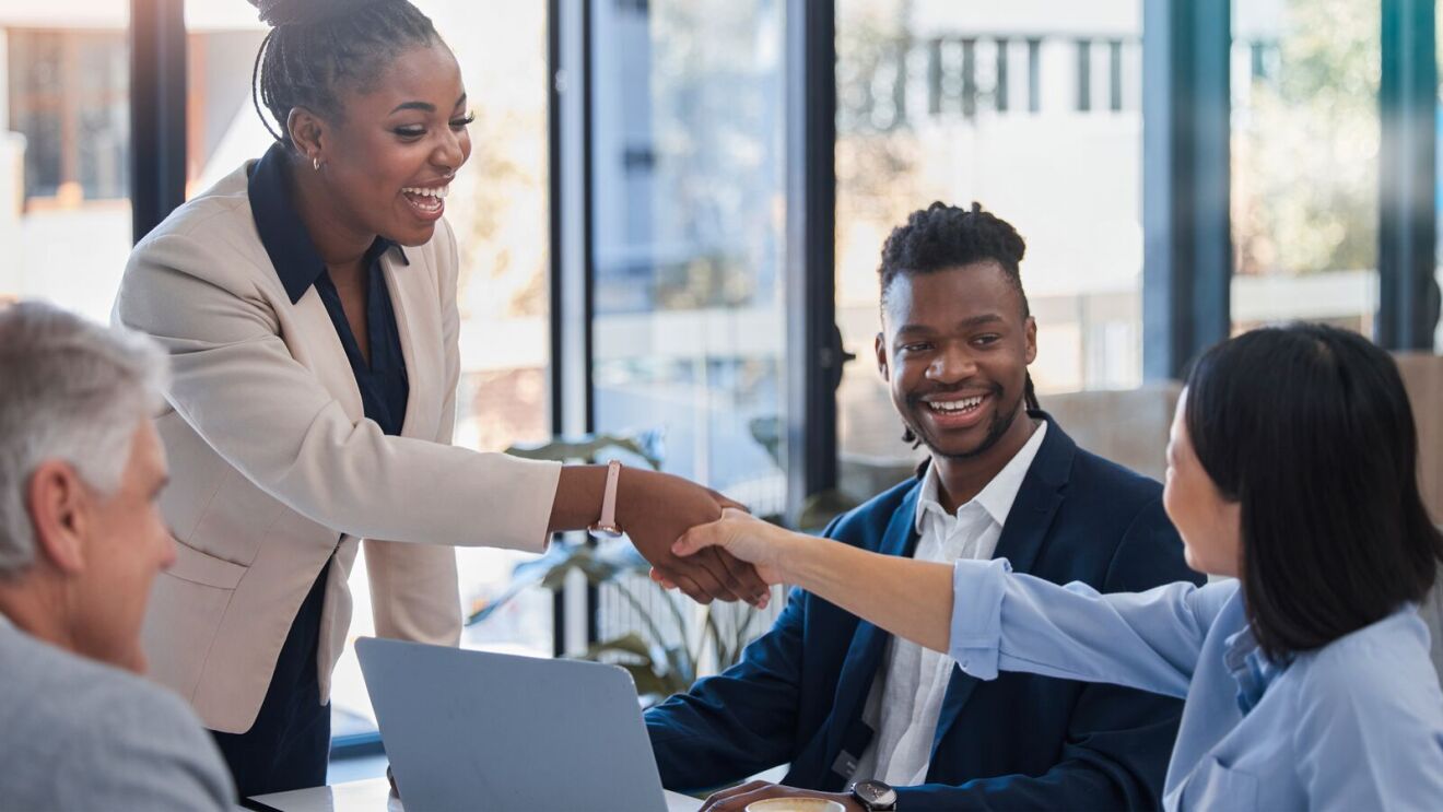 Business professionals shaking hands in bright office meeting.