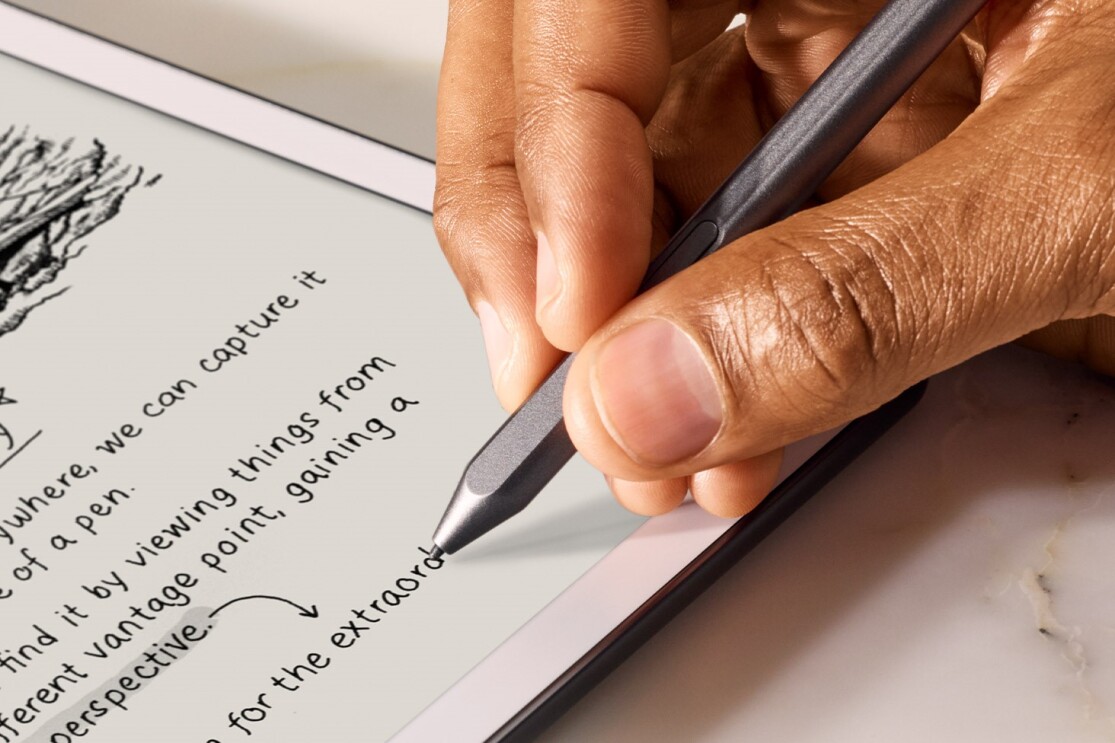 白いタブレットにスタイラスペンで手書きで英文を書いている。手のクローズアップ