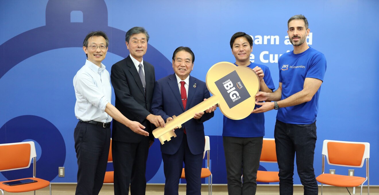 Think Bigと書かれた大きな鍵のモニュメントを手にする5人