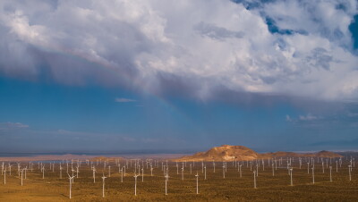 An aerial view of a wind farm in a mountainous desert landscape.