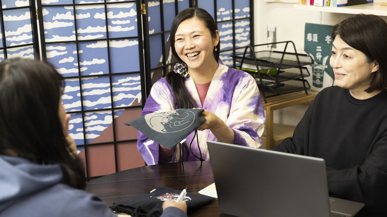 女性スタッフと笑顔でミーティングしている様子の穴沢さん