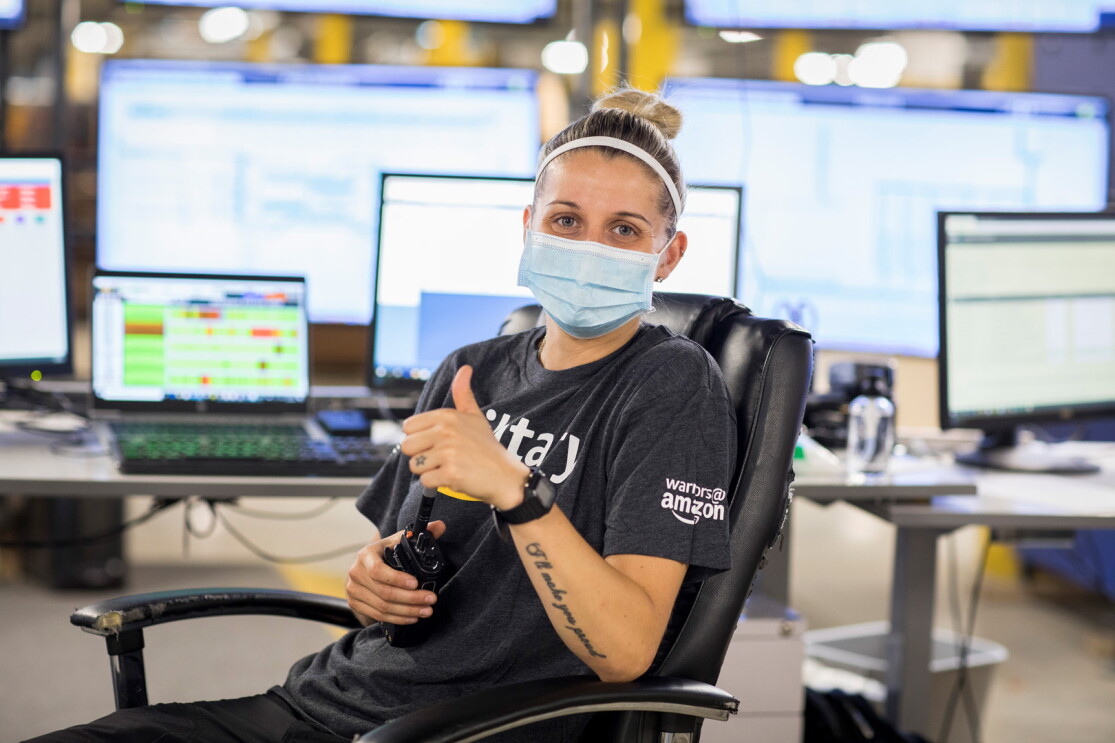 An image of an Amazon employee working at Amazon while wearing a shirt that says "military" with the Amazon logo under it.