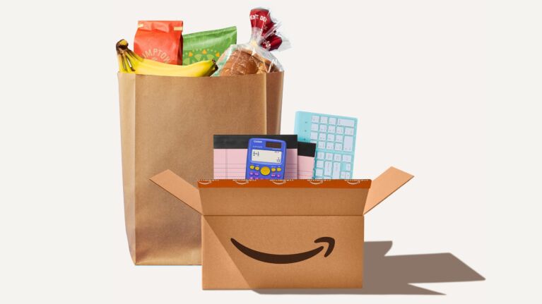 Amazon delivery box with groceries in a paper bag and office supplies including calculator and keyboard