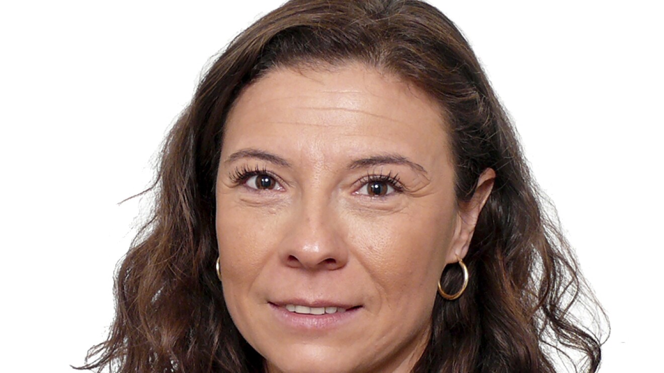 Carmen María Martínez Martínez-Burbana, responsable de Relaciones Laborales. Mirando a cámara con el pelo largo, castaño y ondulado. Con pendientes, sonriente y camisa gris. LLeva un jersy de punto negro con volantes en los hombros.
