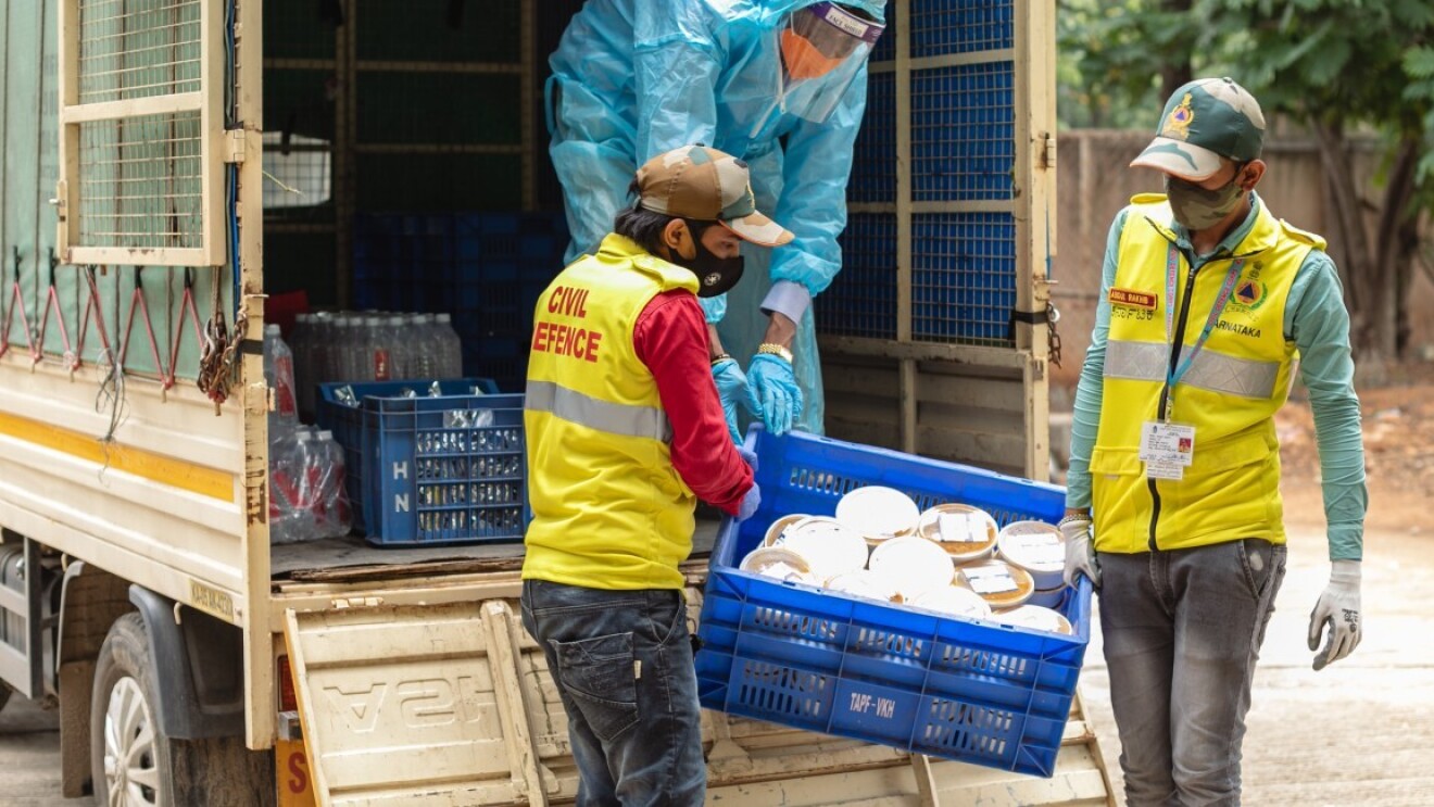 Two persons unloading relief material which will aid the commuity during COVID 