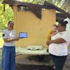 Cooperante de la Fundación Salud Infantil con una tablet delante de una madre con su hijo en brazos. 