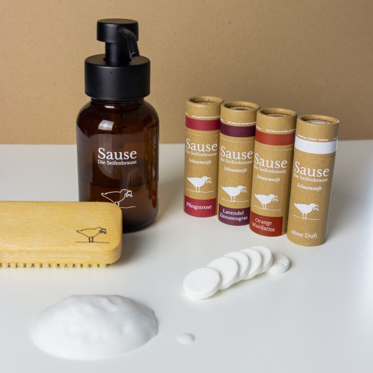 Auf einem Tisch stehen ein Seifenspender, ein Schwamm sowie die Brausetabletten von Seifenbrause.