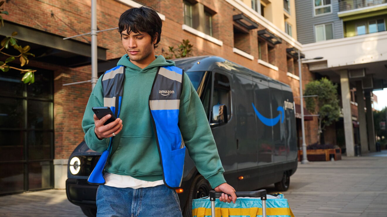 Amazon delivery driver checking phone next to Prime van