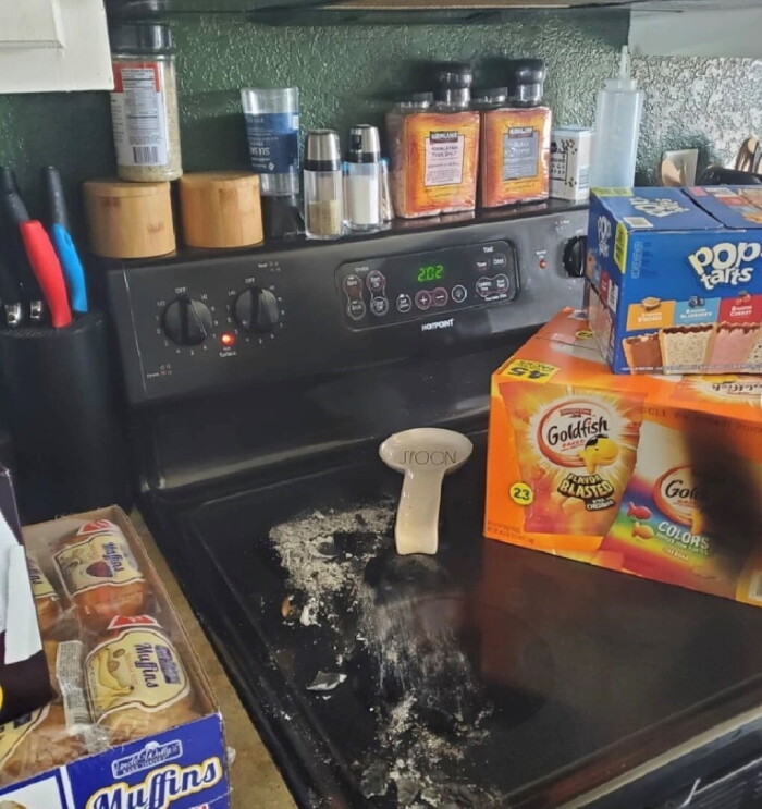 An image of a stove with spices stacked on top of it and food boxes on the burner.