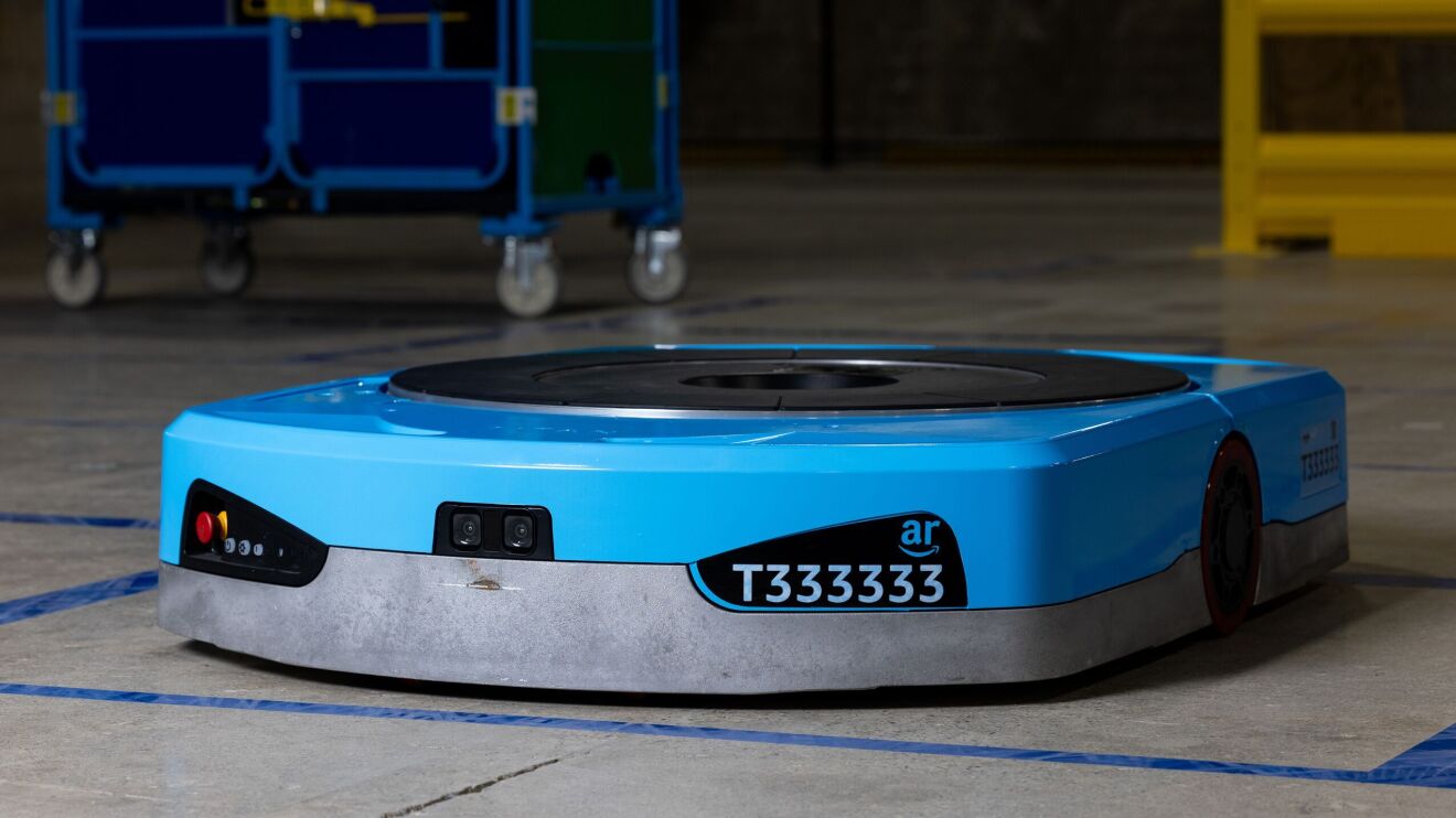 An image of Amazon's new Titan robot. It's blue, plate-like robot with black details, including a camera on the front, a name plate that says