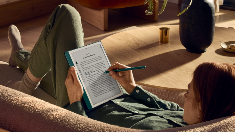 Eine Frau liest und schreibt entspannt mit dem Kindle Scribe auf dem Sofa.