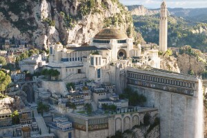 A scene from the Lord of the Rings: The Rings of Power. There is a large city on a hill with a big structure in the middle depicting a court in Numenor.