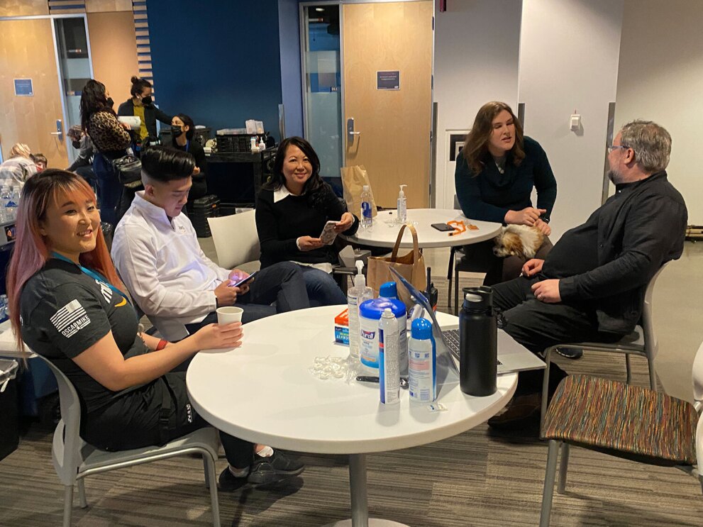 An image of a group of people sitting around a table talking to one another.