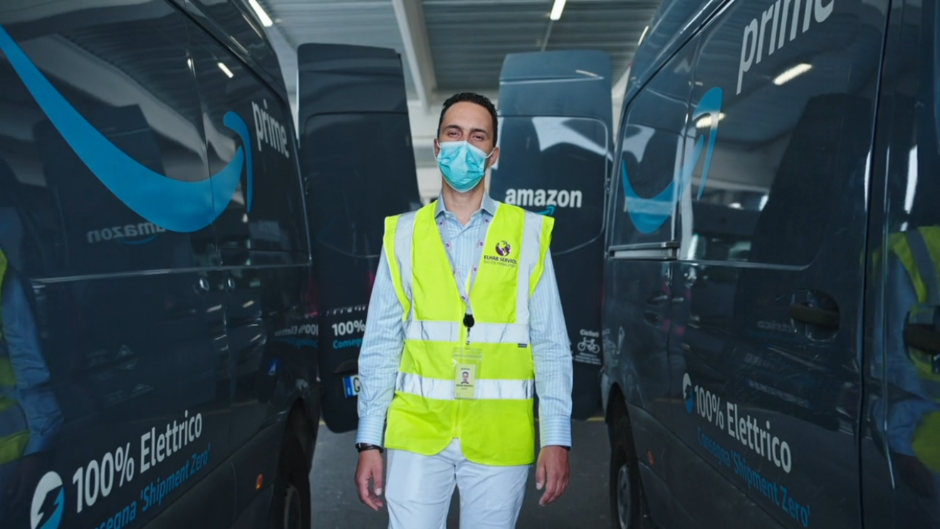 A photo of a man in a vest in-between electric delivery vans
