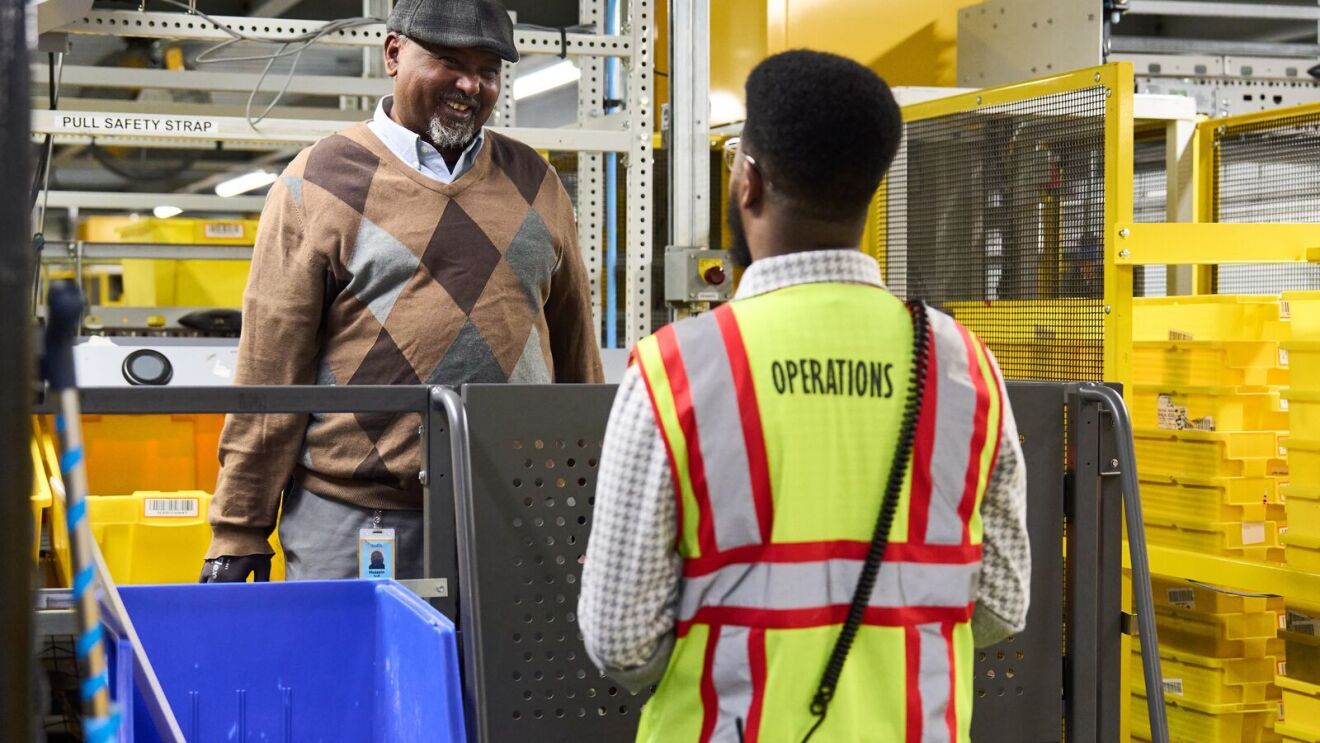 An image of two men speaking to each other in an Amazon fulfillment center.