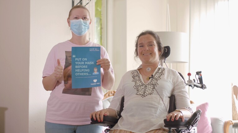 Eine Pflegekraft neben einer jungen Frau im Rollstuhl