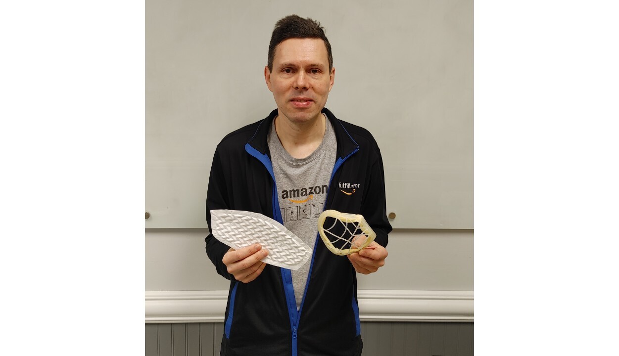 Dmytro Pogrebnoy holds up the cloth of the mask and a 3D print of the mask.