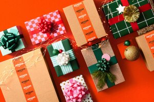 An image of wrapped holiday presents with Christmas lights. There is an orange background behind them.